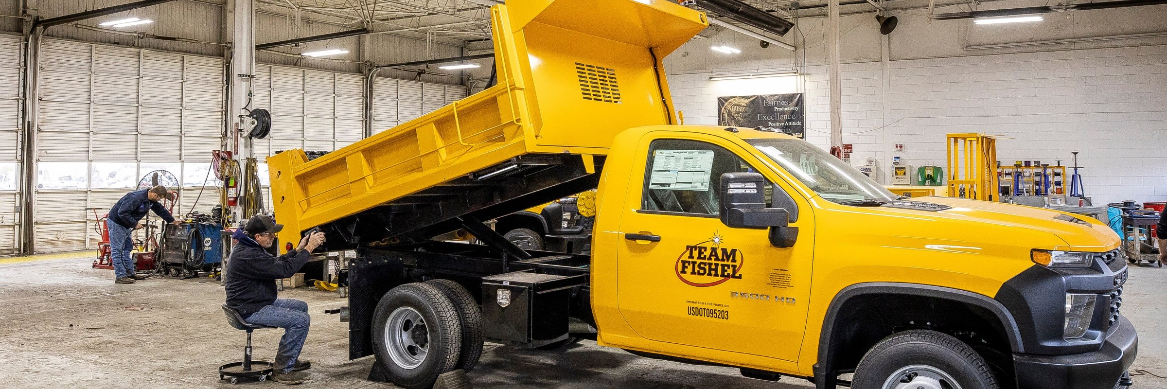 technician installing dump body on truck